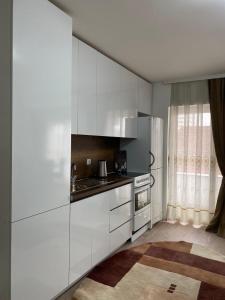 cocina con armarios blancos y fogones en White Apartments, en Kosovo Polje