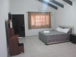 a bedroom with a bed and a television in it at Moony’s Chalets & Camping in Catembe