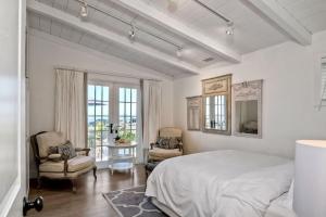 a white bedroom with a bed and two chairs at Ocean Views, Across The Street From Beach, Private Patio in Carlsbad