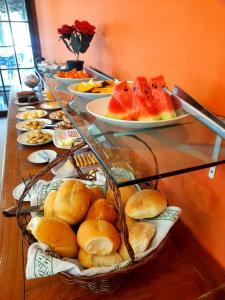 a buffet line with plates of bread and fruit at Hotel Pousada Rio Mar in Ubatuba