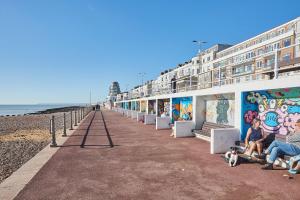 un groupe de personnes assises sur un banc sur la plage dans l'établissement Beautiful Sea View Apartment in St Leonards on Sea, à St. Leonards