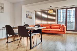 a living room with a table and an orange couch at Cozy Apartment with Mountain View & Parking in Sofia