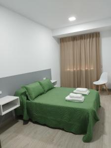 a bedroom with a green bed with towels on it at HORIZON in Arzúa