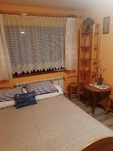 sypialnia z łóżkiem, oknem i stołem w obiekcie Pokoje u Lusi w mieście Białka Tatrzanska