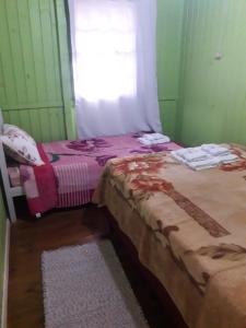 two beds in a room with a window at pousada alternativa dora in Urubici