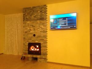 a fireplace with a tv on a yellow wall at Zlatina Guest House in Lŭga