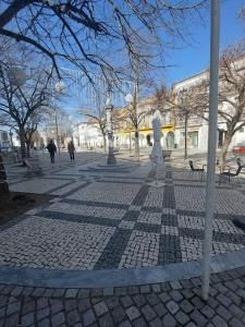 a cobblestone street with a statue in a park at GALLE - Apartamento dos Infantes in Beja