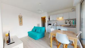 une cuisine et une salle à manger avec une table et une chaise bleue dans l'établissement Appartement Les Embruns, à Saint-Gilles-Croix-de-Vie