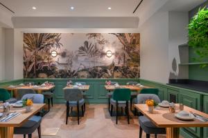 ein Esszimmer mit Tischen und Stühlen und einem Wandgemälde in der Unterkunft Hotel Cambon in Paris