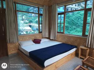 a bed in a room with two windows at The MoonLight Stay - Shimla in Shimla