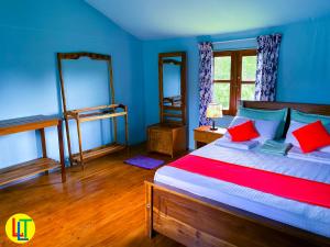 1 dormitorio con 1 cama con paredes azules y almohadas rojas en mango villa wilpattu, en Nekattegama