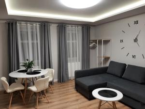 salon z kanapą, stołem i zegarem w obiekcie Central Platinum Apartments 14 w Rybniku