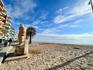 a statue on a beach next to a building at Prop de mar a 60m de la playa in Calafell
