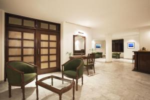 a living room with chairs and a table and a mirror at Hotel Alpana in Haridwār