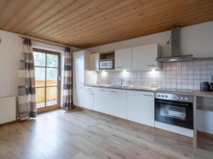 een keuken met witte apparatuur en een houten plafond bij Haus Durchegg UG in Wagrain