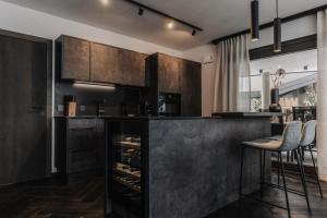 a kitchen with black cabinets and a bar with stools at ONKL XONNA Premium Alpin Chalets in Hüttschlag
