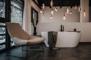 a bathroom with a tub and a chair and lights at ONKL XONNA Premium Alpin Chalets in Hüttschlag