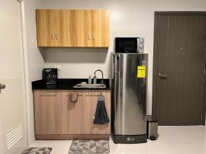 a kitchen with a stainless steel refrigerator and wooden cabinets at 7F Majorca, Camella Manors Bacolod Condo in Bacolod