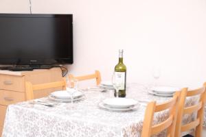 a dining table with a bottle of wine and glasses at Apartman Vuvuzela in Kupres