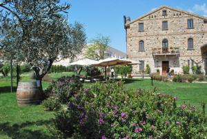 un grande edificio in pietra con un ombrello e alcuni fiori di Locanda Dei Cocomeri a Montalto Uffugo