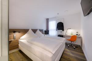 a bedroom with a white bed and a desk and a chair at CiTTy Hotel Schweinfurt in Schweinfurt