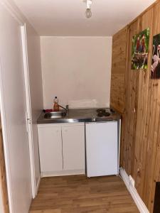 una pequeña cocina con armarios blancos y fregadero en La Dilichambre, en Carcagny