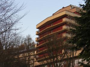un edificio de apartamentos alto con árboles en el primer plano en SP ZOZ Sanatorium Uzdrowiskowe MSWiA w Krynicy-Zdroju, en Krynica-Zdrój