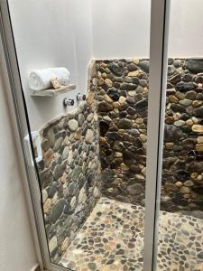 a bathroom with a shower with a stone wall at Casa Biznaga in Oaxaca City +74 photos
