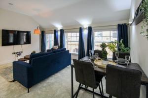 a living room with a blue couch and a dining table at Luxurious 2 Bedroom Apartment in City Centre in Nottingham