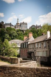 un antiguo edificio en una ciudad con edificios en una colina en Mercier de Montigny - Les Chambres du Beffroi - SPA et Massage, en Fougères