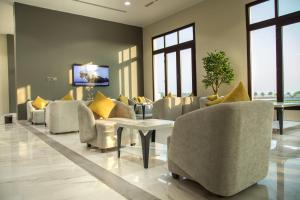 un soggiorno con divano, sedie e TV di Continent Hotel Al Uqayr فندق كونتننت العقير 