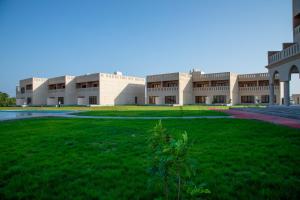 ein großes Gebäude mit grünem Rasen davor in der Unterkunft Continent Hotel Al Uqayr فندق كونتننت العقير 