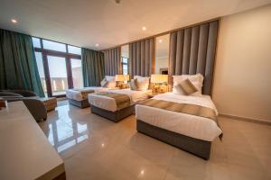 a hotel room with two beds and a couch at Continent Hotel Al Uqayr فندق كونتننت العقير 