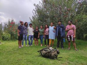 eine Gruppe von Menschen, die neben einer Tüte auf dem Gras stehen in der Unterkunft The Hideout - Hiraeth in Manali