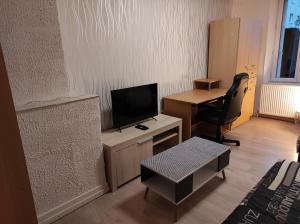 uma sala de estar com uma secretária, uma televisão e uma cadeira em Appartement calme dans quartier résidentiel. em Nancy