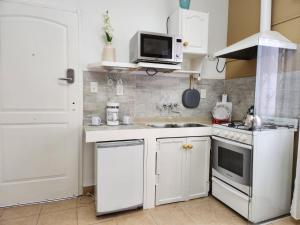 - une petite cuisine avec des placards blancs et un four micro-ondes dans l'établissement Jazmines Apart, à Martínez