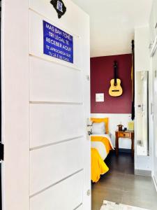 une porte menant à une chambre avec un lit et une guitare dans l'établissement La Casita Bem Gaúcha, à Porto Alegre