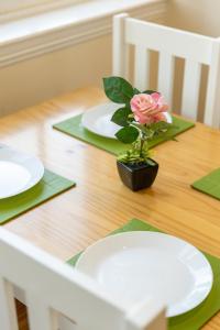 una mesa con platos blancos y una flor rosa en ella en New 2 bed apartment with stunning views of Arthur Seat Mountain en Edimburgo