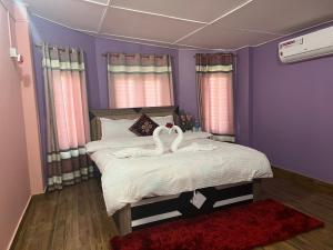 zwei Schwäne auf einem Bett in einem Schlafzimmer in der Unterkunft Old House Villa in Sauraha