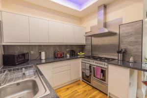 - une cuisine avec des placards blancs et un évier dans l'établissement New 3-Bedroom Apartment Close to City Centre, à Édimbourg
