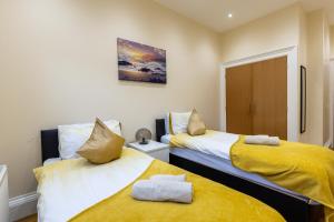 エディンバラにあるNew 3-Bedroom Apartment Close to City Centreの黄色いシーツが備わる客室内のベッド2台