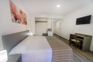 1 dormitorio con 1 cama blanca grande y escritorio en Hostal Anna Benidorm, en Benidorm