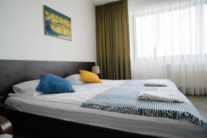 1 dormitorio con 1 cama grande con almohadas azules y amarillas en Jundula, en Šakiai