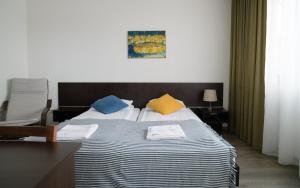 - une chambre avec un grand lit et des oreillers colorés dans l'établissement Jundula, à Šakiai