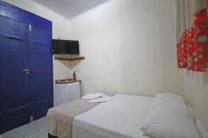 a bedroom with a white bed and a blue door at Pousada Tia Nena in Olímpia