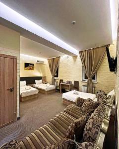 タシュケントにあるAl Arda HOTELのベッド2台とソファが備わるホテルルームです。