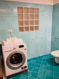 eine Waschmaschine im Bad mit blauen Fliesen in der Unterkunft Central Apartment Private Parking Terrace & AC in Desenzano del Garda