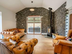 a living room with leather furniture and a brick wall at Ty Afon Arch - Uk38515 in Garnant