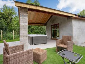 a patio with two chairs and a grill and a hot tub at Ty Afon Arch - Uk38515 in Garnant