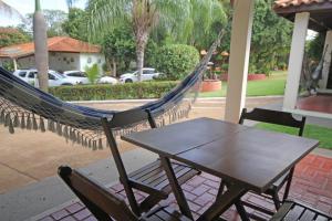 een hangmat en een tafel en stoel op een veranda bij Pousada Tia Nena in Olímpia